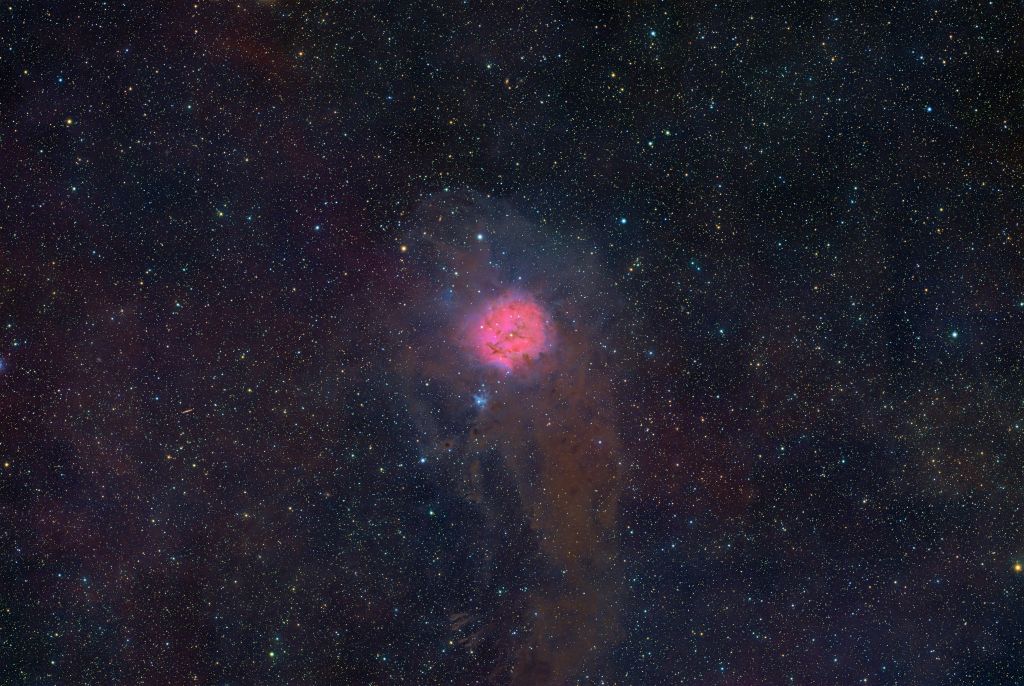 A vibrant astronomical image showcasing a nebula emitting pink and purple hues, surrounded by a field of numerous stars against a dark cosmic background.